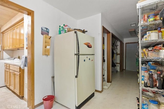 kitchen with light brown cabinets, light floors, light countertops, washer / clothes dryer, and freestanding refrigerator