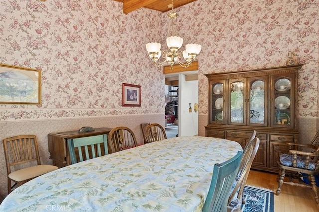 dining space with beam ceiling, a chandelier, and hardwood / wood-style floors