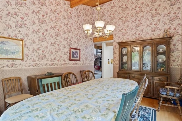dining room with a chandelier, wood finished floors, and wallpapered walls