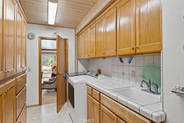 laundry area with cabinet space, washing machine and dryer, wood ceiling, and a sink
