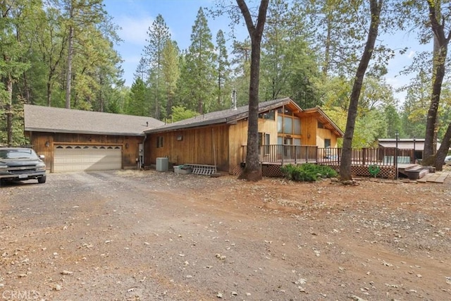 view of side of home featuring central AC unit, driveway, a deck, and a garage