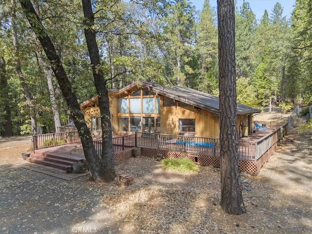 exterior space with a forest view, crawl space, and a deck