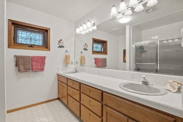 bathroom featuring tile patterned floors, double vanity, a sink, baseboards, and a stall shower