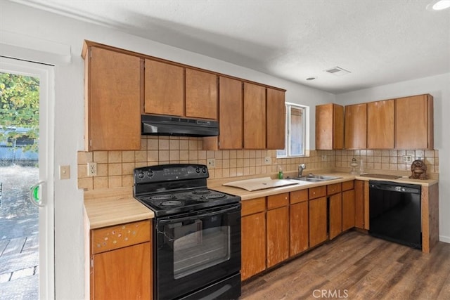 kitchen featuring black appliances, decorative backsplash, sink, dark hardwood / wood-style flooring, and a textured ceiling