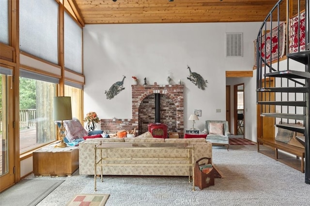 living room with wooden ceiling, high vaulted ceiling, carpet, and a wood stove