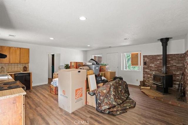 interior space featuring visible vents, baseboards, recessed lighting, wood finished floors, and a wood stove