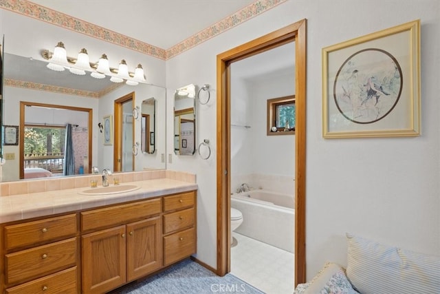 bathroom featuring a relaxing tiled tub, vanity, and toilet