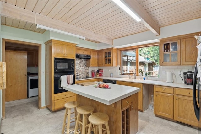 kitchen featuring wooden ceiling, a kitchen island, decorative backsplash, black appliances, and a kitchen bar