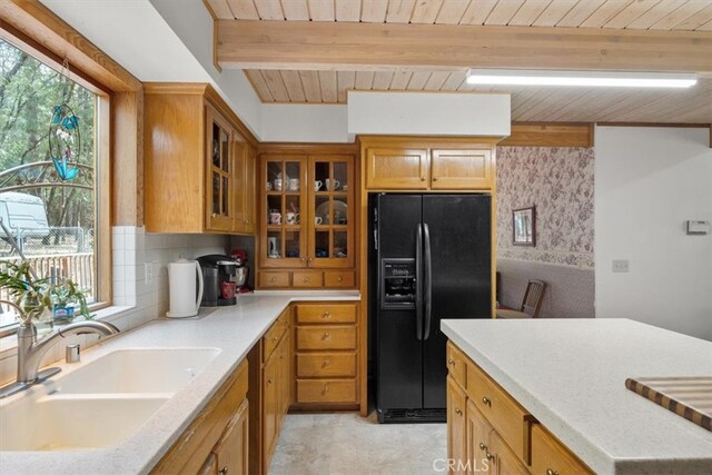 kitchen with beamed ceiling, sink, black refrigerator with ice dispenser, and wooden ceiling