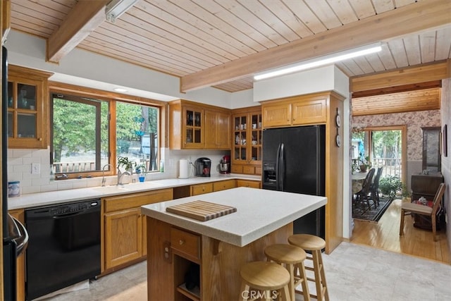 kitchen with a kitchen island, black appliances, a healthy amount of sunlight, and light wood-type flooring