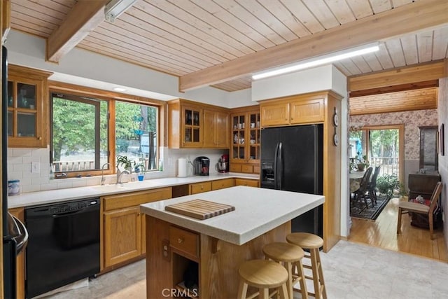kitchen featuring beam ceiling, wood ceiling, a sink, and black appliances