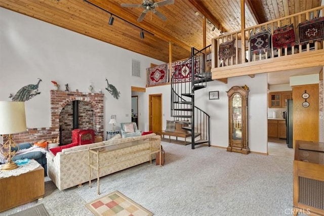 living area with stairs, ceiling fan, wooden ceiling, high vaulted ceiling, and a wood stove