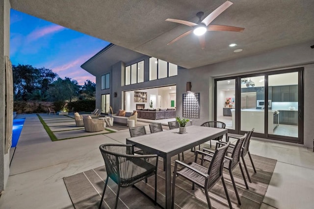 patio terrace at dusk with an outdoor living space with a fire pit and ceiling fan