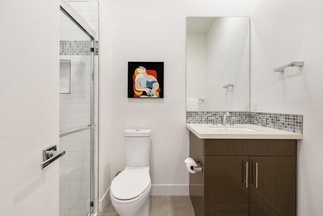 bathroom with vanity, backsplash, a shower with shower door, and toilet