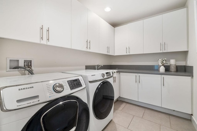 clothes washing area featuring cabinets, light tile patterned floors, and washer and dryer