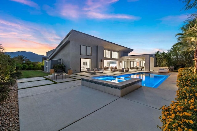 back house at dusk with a swimming pool with hot tub, an outdoor living space, a mountain view, and a patio