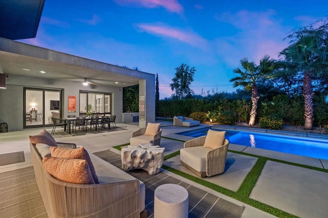 pool at dusk with ceiling fan and a patio