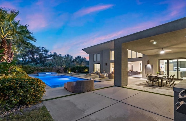 pool at dusk featuring a patio and ceiling fan