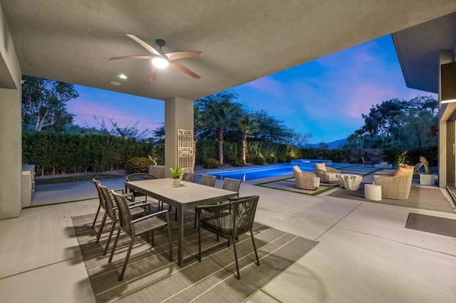 patio terrace at dusk with a fenced in pool and ceiling fan