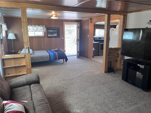 carpeted bedroom with access to outside, wood walls, and ceiling fan