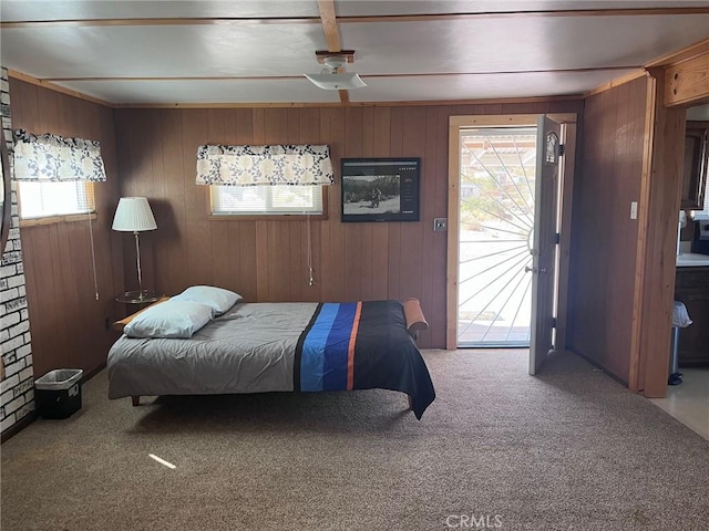 carpeted bedroom with wooden walls, ceiling fan, and access to outside