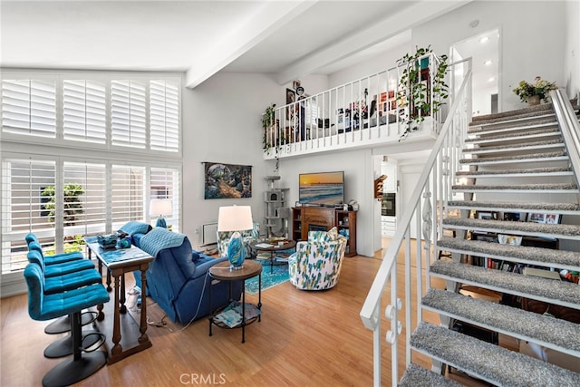 living room with beamed ceiling, wood-type flooring, and a high ceiling