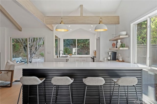 kitchen featuring sink, pendant lighting, lofted ceiling with beams, and hardwood / wood-style floors