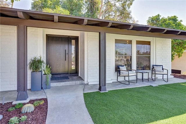 property entrance featuring covered porch and a lawn