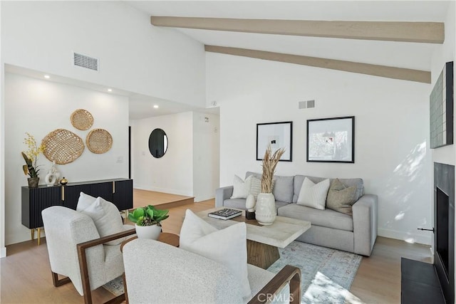 living room with beamed ceiling, high vaulted ceiling, and light wood-type flooring