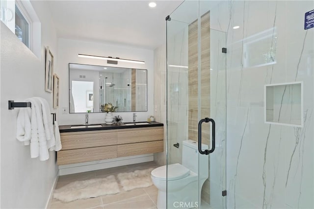 bathroom with tile patterned floors, vanity, a shower with shower door, and toilet