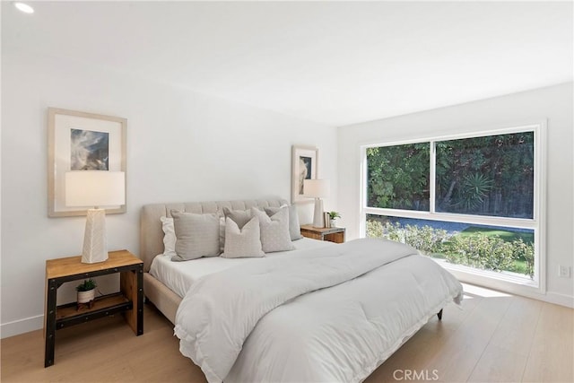 bedroom with multiple windows and light hardwood / wood-style flooring