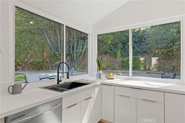 kitchen featuring dishwasher, white cabinets, vaulted ceiling, and sink