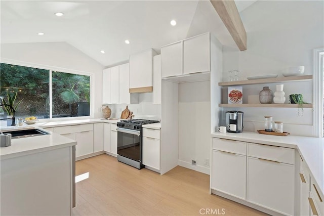 kitchen with white cabinets, light hardwood / wood-style floors, lofted ceiling, and stainless steel range with gas stovetop