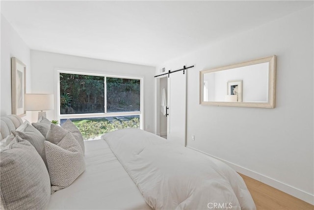 bedroom with a barn door and wood-type flooring