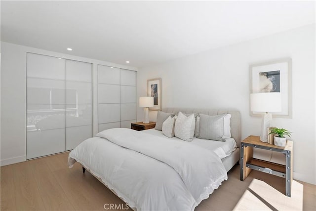 bedroom with light wood-type flooring and multiple closets