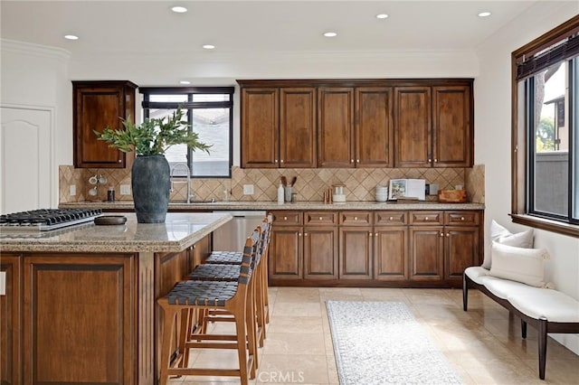 kitchen featuring tasteful backsplash, light stone countertops, plenty of natural light, and appliances with stainless steel finishes