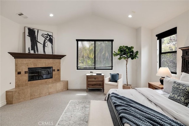 carpeted bedroom featuring a tile fireplace and lofted ceiling