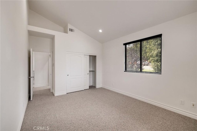 unfurnished bedroom with carpet flooring, a closet, and vaulted ceiling