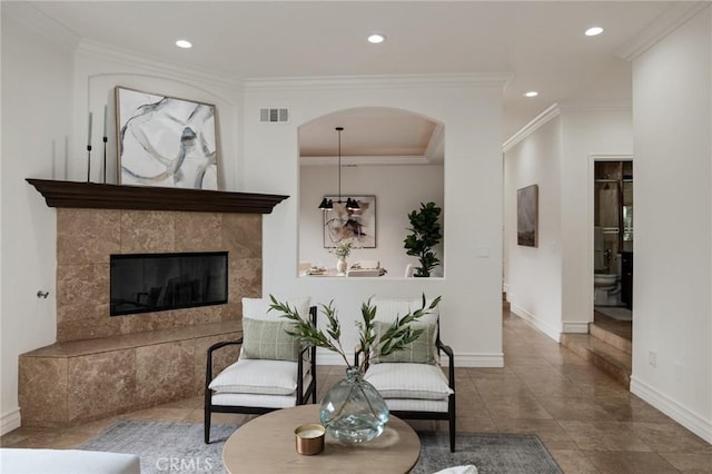 tiled living room featuring crown molding and a tile fireplace