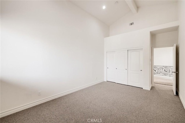 unfurnished bedroom featuring beam ceiling, a closet, and carpet