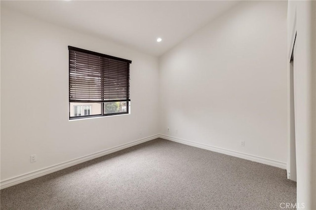 carpeted spare room with lofted ceiling