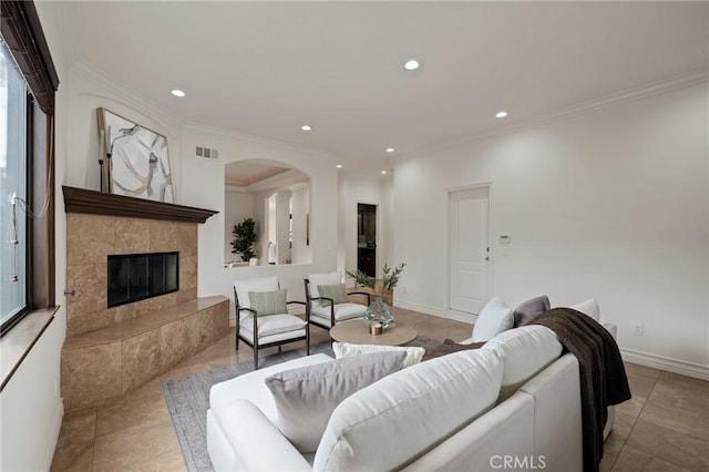 tiled living room with crown molding and a tiled fireplace