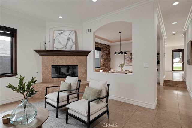 sitting room with a tile fireplace, light tile patterned floors, and crown molding