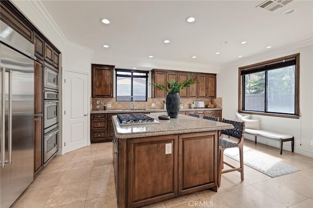 kitchen featuring built in appliances, decorative backsplash, a center island, and a wealth of natural light