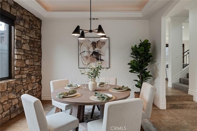 tiled dining area featuring a chandelier, a raised ceiling, and crown molding