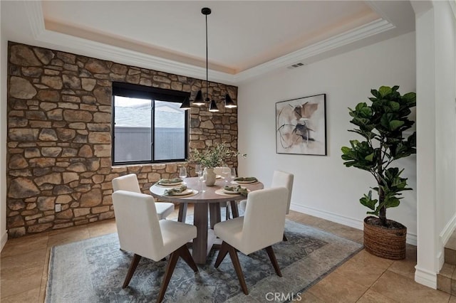 dining space with a raised ceiling, ornamental molding, and an inviting chandelier