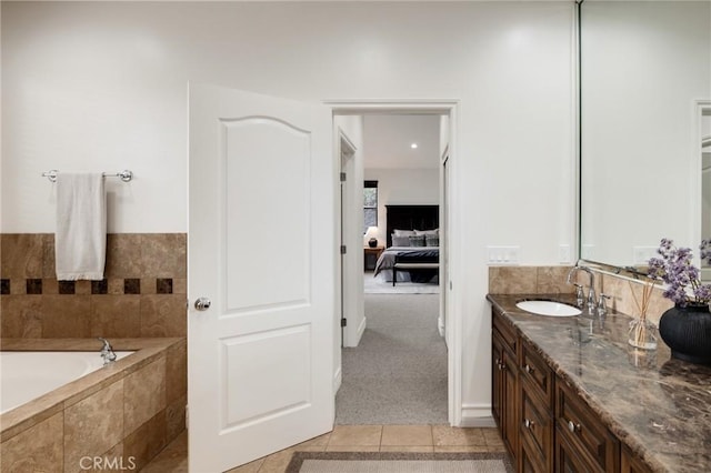 bathroom with tile patterned flooring, vanity, and tiled bath