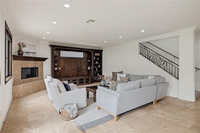 living room with a tiled fireplace and crown molding