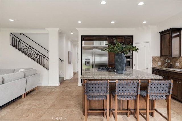 kitchen featuring a kitchen breakfast bar, a center island, stainless steel appliances, and dark brown cabinetry