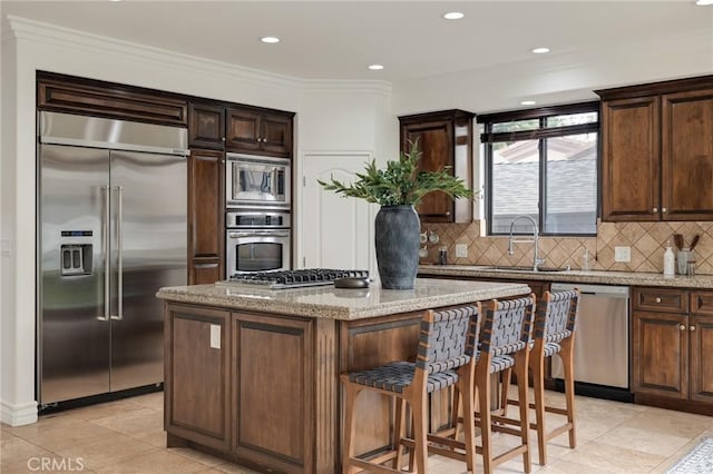 kitchen featuring built in appliances, a kitchen island, and light stone countertops